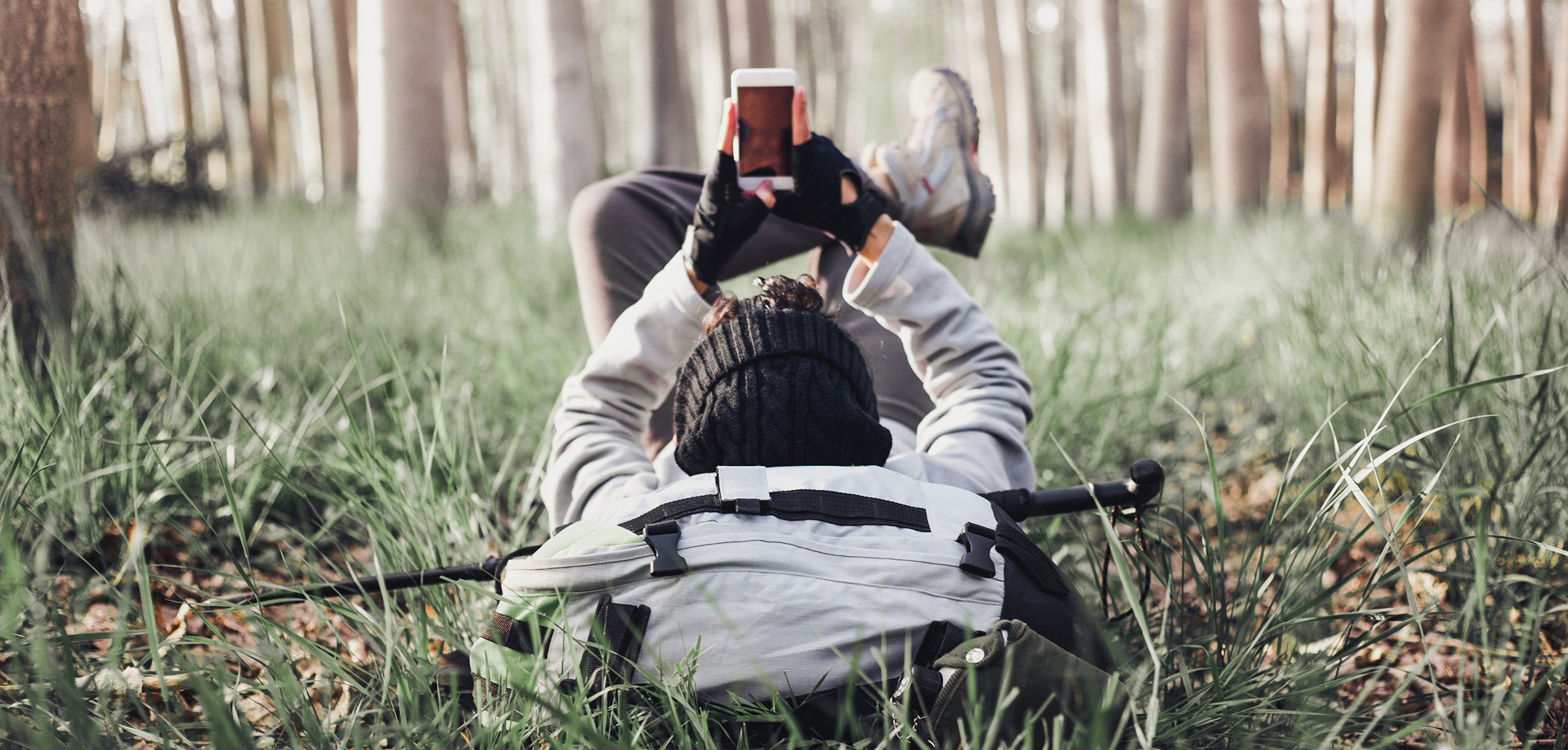 Hiker lying on back in woods using mobile device